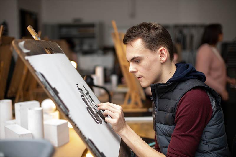 male student drawing on a pad